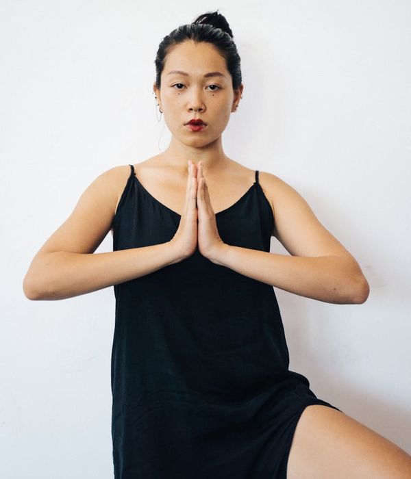 Person holding a difficult balance yoga pose against a minimal background.